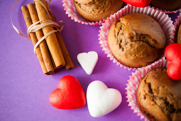muffins and cinnamon with hearts on purple background