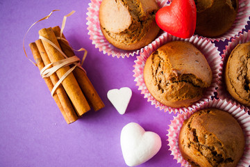 muffins and cinnamon with hearts on purple background