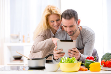 Young attractive couple reading recipe on a  tablet