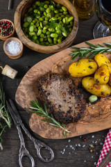 Beef steak with roasted potatoes and herbs, top view