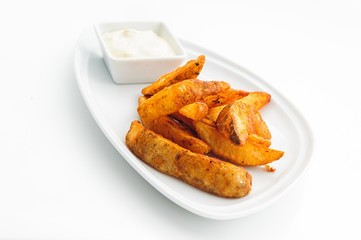 Fried potatoes on white plate with sauce
