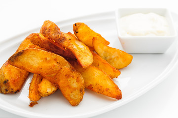 Fried potatoes on white plate with sauce