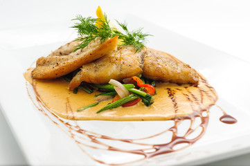 Fried fish fillet with sauce on a white plate
