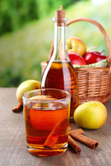 Apple cider in glass and bottle, with cinnamon sticks and fresh