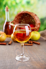 Apple cider in wine glass and bottle, with cinnamon sticks and