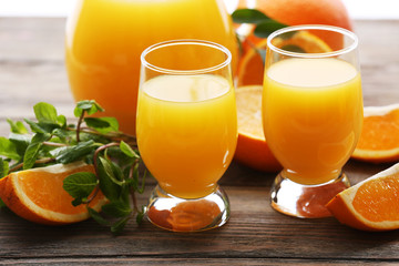Glass of orange juice and slices on wooden table background
