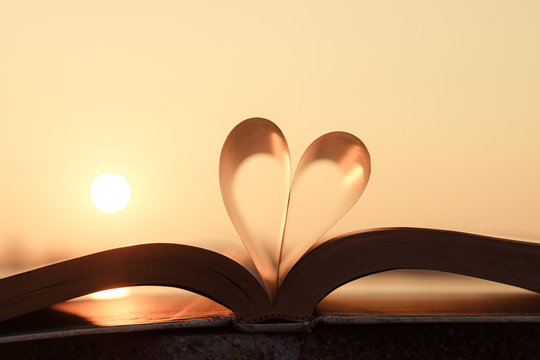 Heart from book pages with warm sunlight