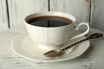 Cup of coffee with beans on color rustic wooden background