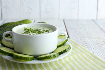 Cucumber soup in bowl on color wooden table background