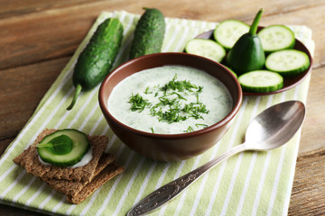 Cucumber soup in bowl on rustic wooden table background