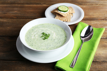 Cucumber soup in bowl on rustic wooden table background