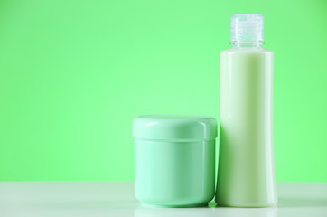 Cosmetic bottles on light green background