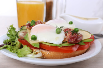 Sandwich with poached eggs, bacon and vegetables