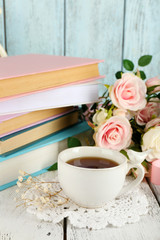 Obraz na płótnie Canvas Cup of tea with books and flowers on wooden background