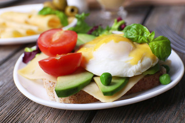 Fototapeta na wymiar Toast with egg Benedict and avocado on plate on wooden table