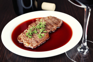Glass of wine with steak on wooden background
