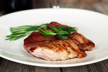 Steak with herbs on plate on wooden table