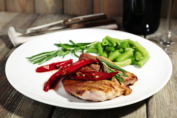Steak with vegetables on plate on table close up