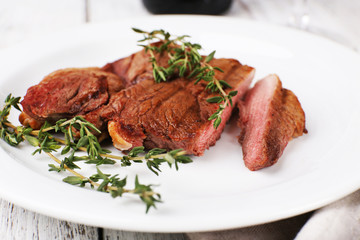 Steak with herbs on plate on wooden table