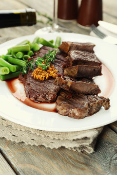 Steak with wine sauce on plate on wooden table