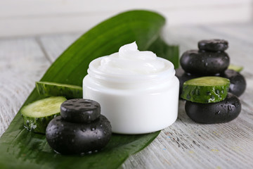Fototapeta na wymiar Cosmetic cream with slices of cucumber and spa stones