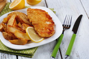 Breaded fried fish fillet and potatoes with sliced lemon