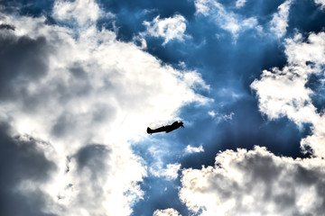 Spitfire silhouette on dark blue sky and snow white clouds