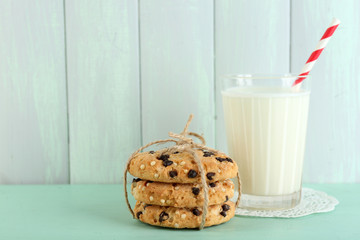 Tasty cookies and glass of milk on color wooden background