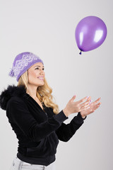 Fototapeta premium Teenage girl in purple knit hat playing with purple balloon