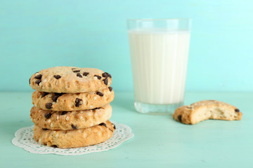 Tasty cookies and glass of milk on color wooden background