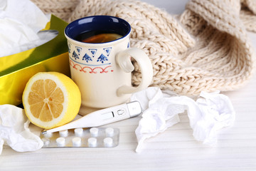Hot tea for colds, pills and handkerchiefs on table close-up