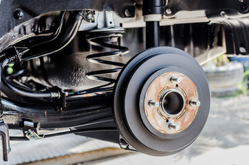 Front disc brake on car in process of new tire replacement. The