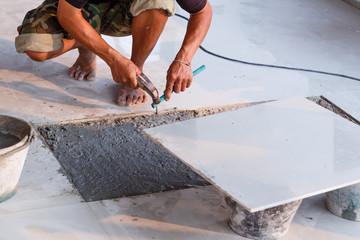 Labor installing tile floor for new house building