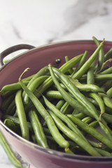 Close up of a pink colander with washed green beans