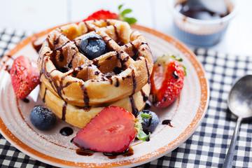 waffles with strawberry ,blueberry poured with chocolate