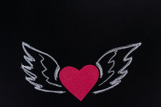 paper heart with pictured chalk wings on black background