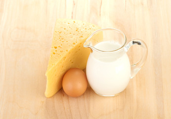 Big piece of cheese, glass jug with milk