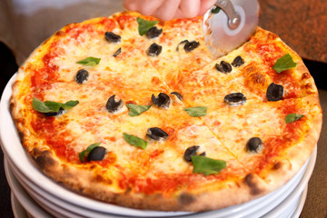 Pizza on plate being cut.