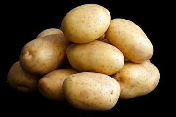 Pile of potatoes arranged on black.