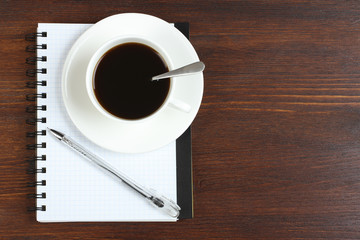Obraz na płótnie Canvas Cup of coffee, pen and opened notepad on desk. Top view