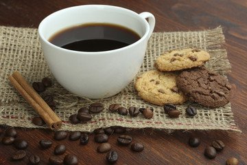 chocolate cookies and cup of hot coffee on old wooden table.