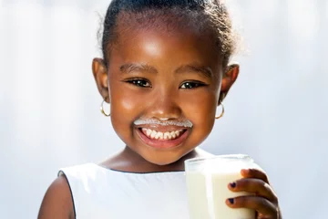Foto auf Acrylglas Milchshake Nettes afrikanisches Mädchen, das weißen Milchschnurrbart zeigt.