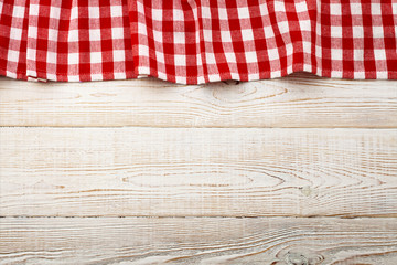 Top view of checkered tablecloth on white wooden table.