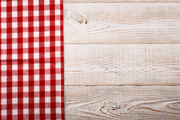 Top view of checkered tablecloth on white wooden table.