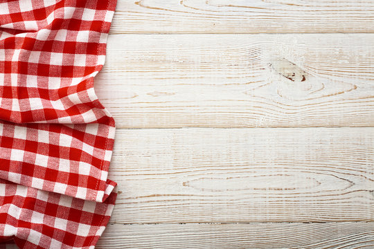 Top view of checkered tablecloth on white wooden table.