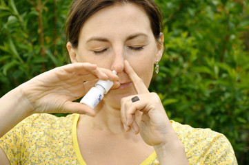 Frau mit Erkältung benutzt Nasenspray