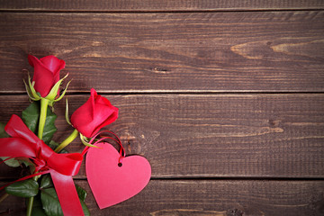 Valentine background of gift tag and red roses on wood. Space fo