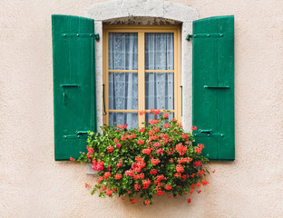 Fototapeta na wymiar Vintage window with flowers and shutters in Switzerland