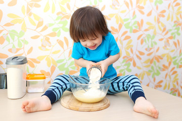 cute little child cooks sitting on a table at home kitchen