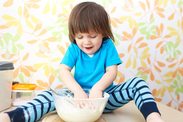 happy 2 years boy cooks sitting on a table at home kitchen